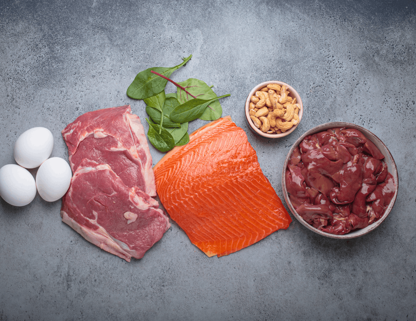A selection of iron-rich foods for pregnancy including red meat, salmon, liver, eggs, spinach and nuts, showing haem and non-haem iron sources