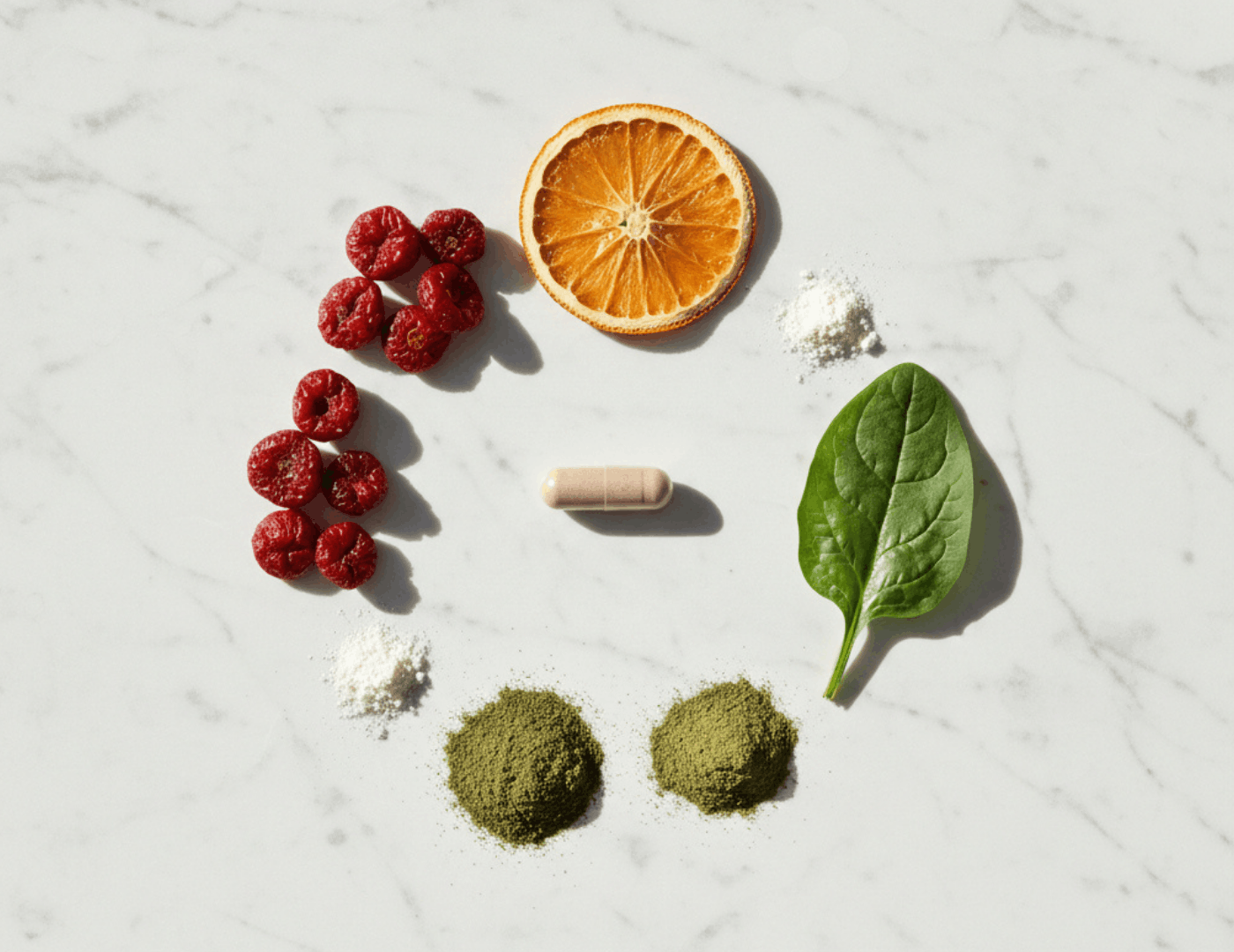 Iron absorption cofactors arranged in a flat lay including vitamin C, spinach, berries, orange and supplement powder, showing nutrients that enhance iron uptake