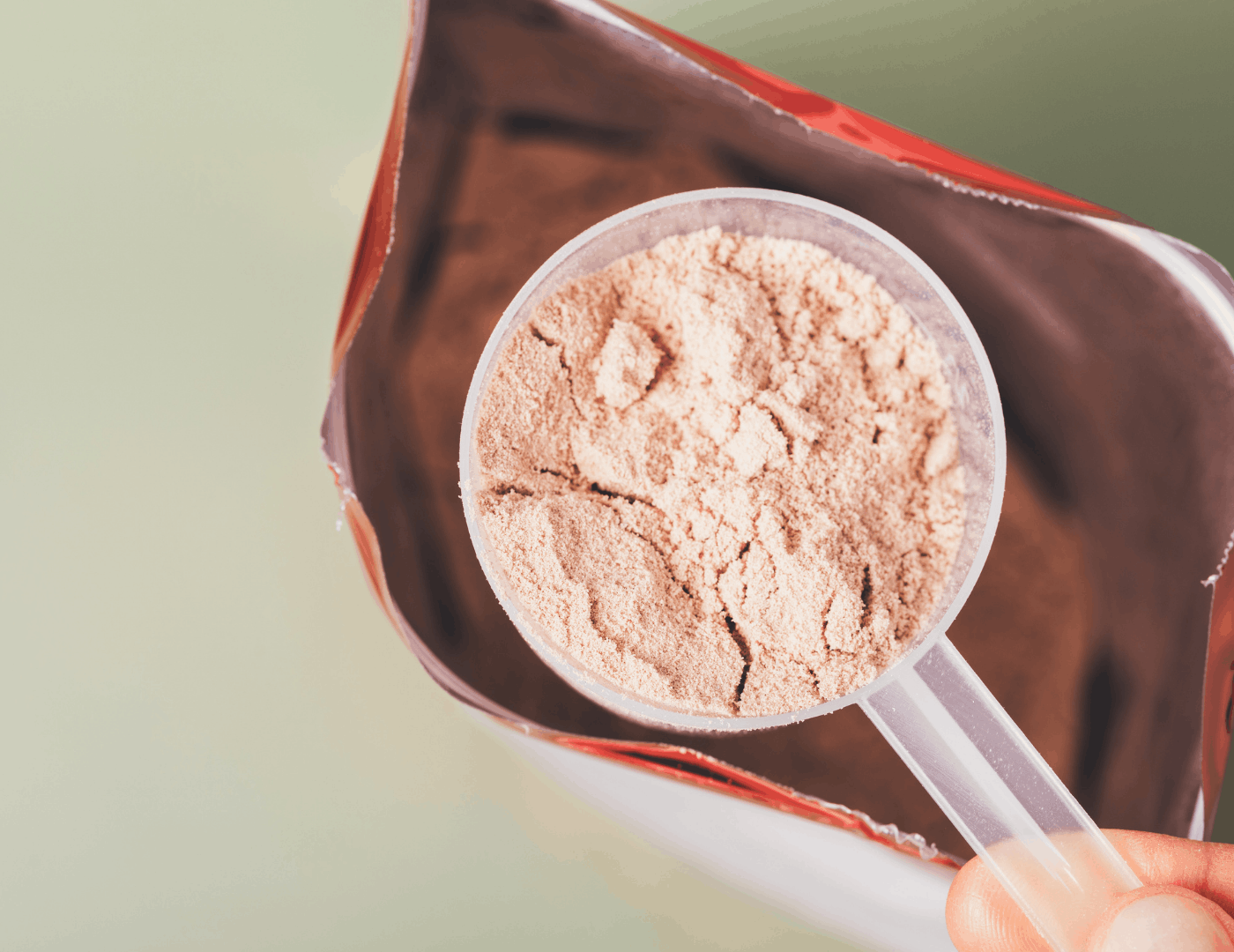 scoop of lactoferrin powder resting on a dark supplement pouch, highlighting the key ingredient in iron supplementation support