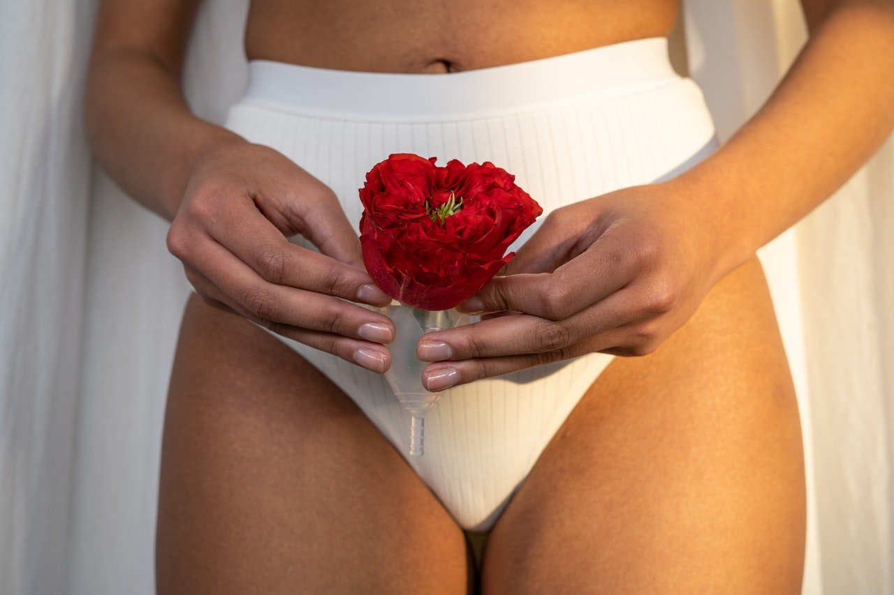 Pregnant woman in white underwear holding a red flower, symbolising vaginal health and Group B Strep awareness in pregnancy.