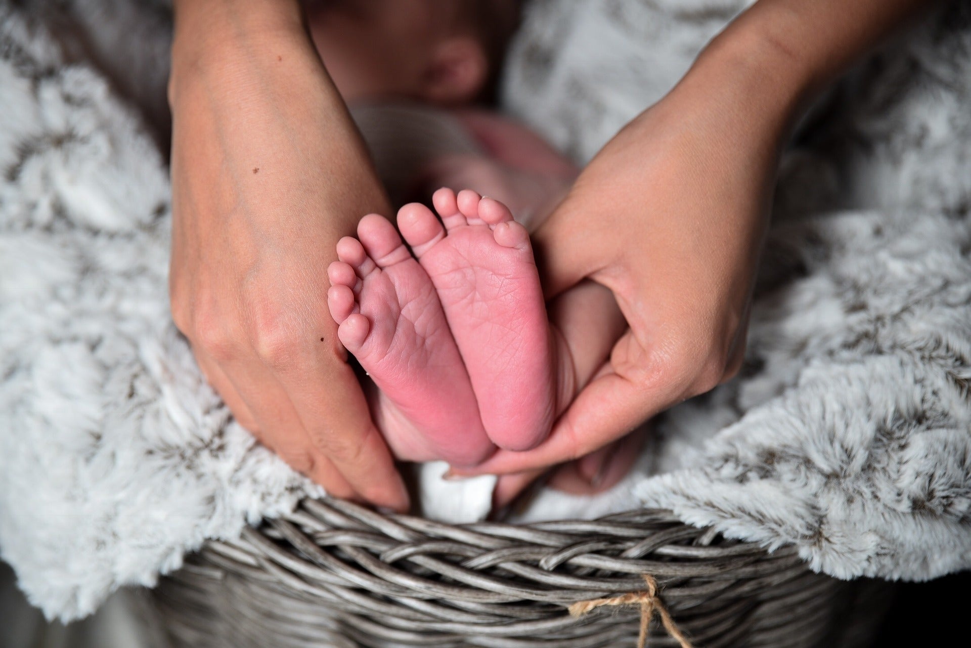 Mother holding newborn’s feet, symbolising the connection between maternal health and the newborn microbiome