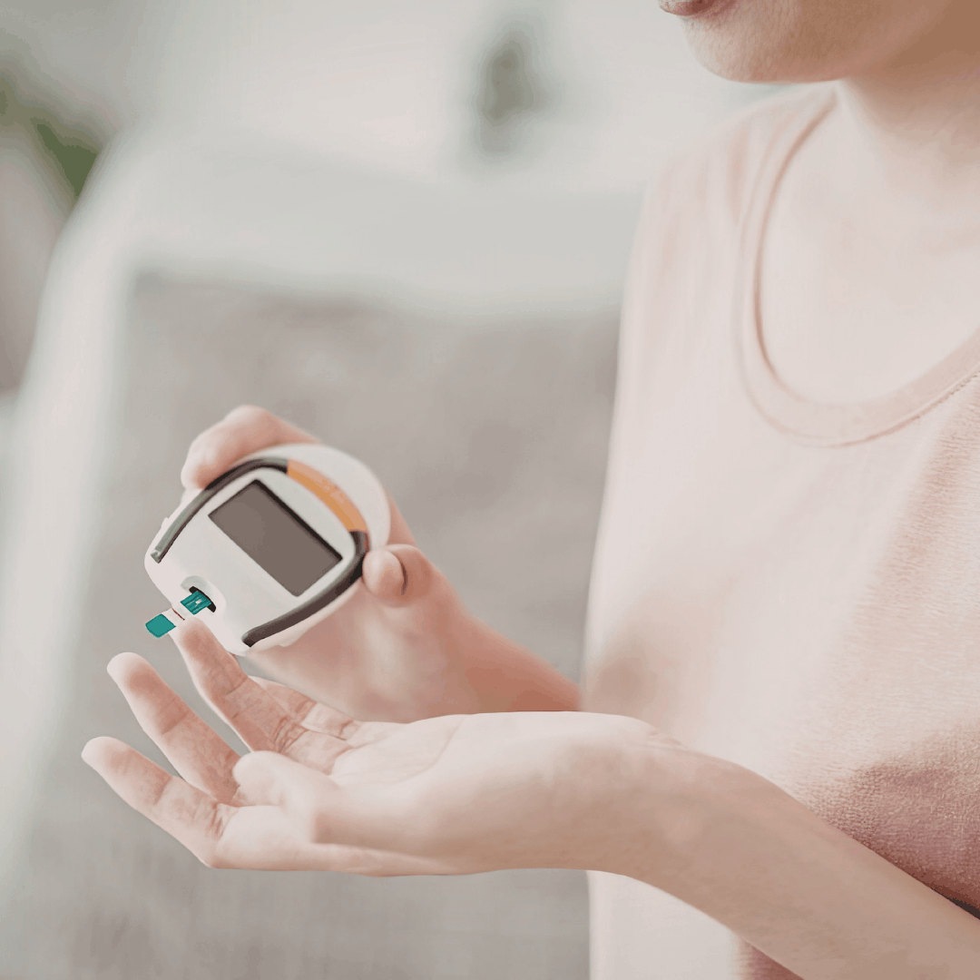 Pregnant woman holding blood glucose monitor to check blood sugar levels during pregnancy