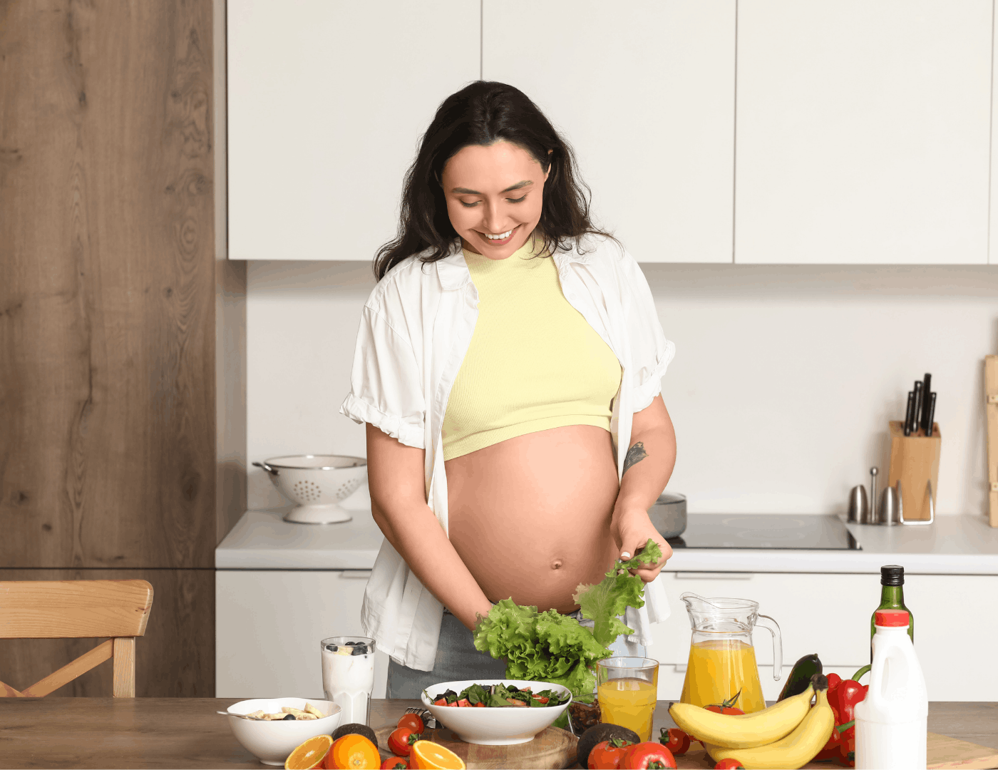 Pregnant woman preparing fresh vegetables and fruit in kitchen to support postpartum nutrition