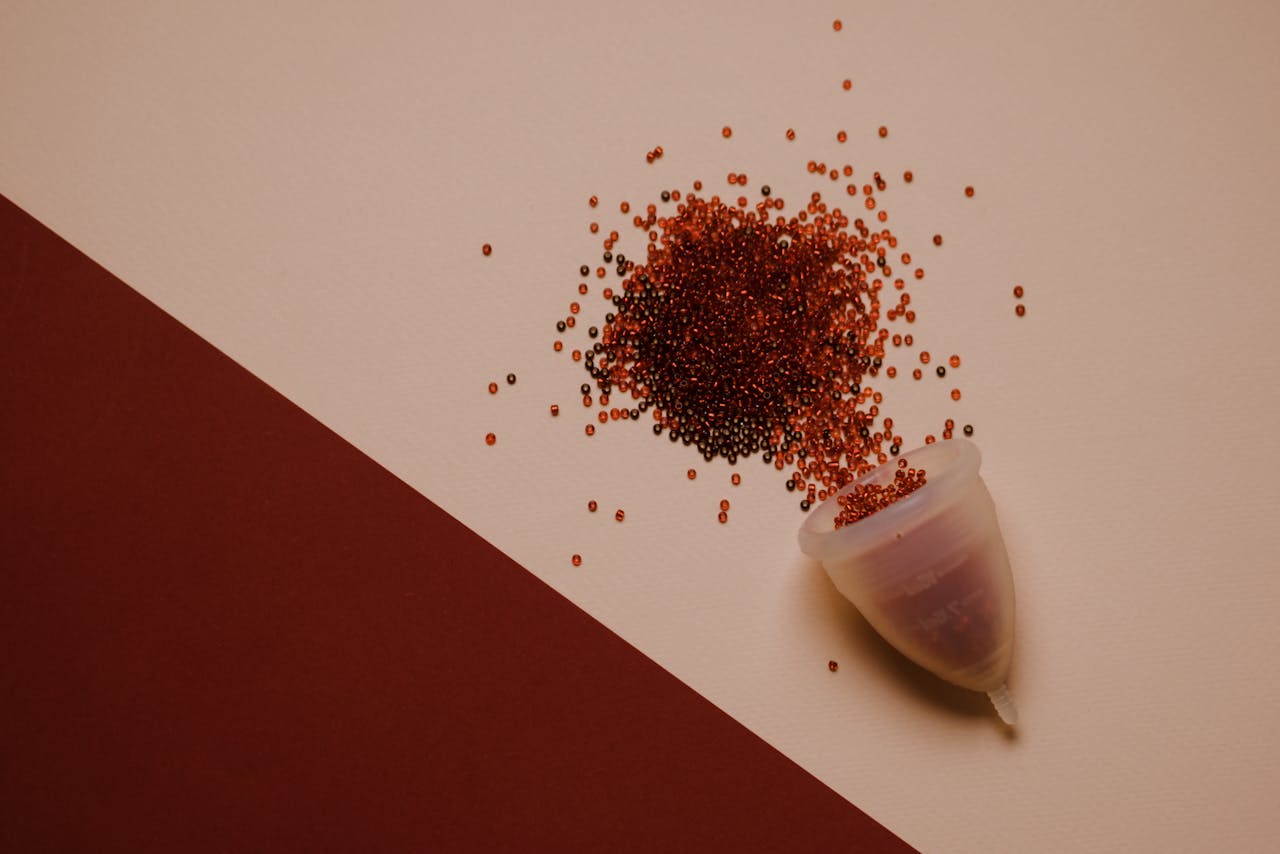 Menstrual cup with red granules representing menstrual flow, symbolising irregular menstrual cycles.