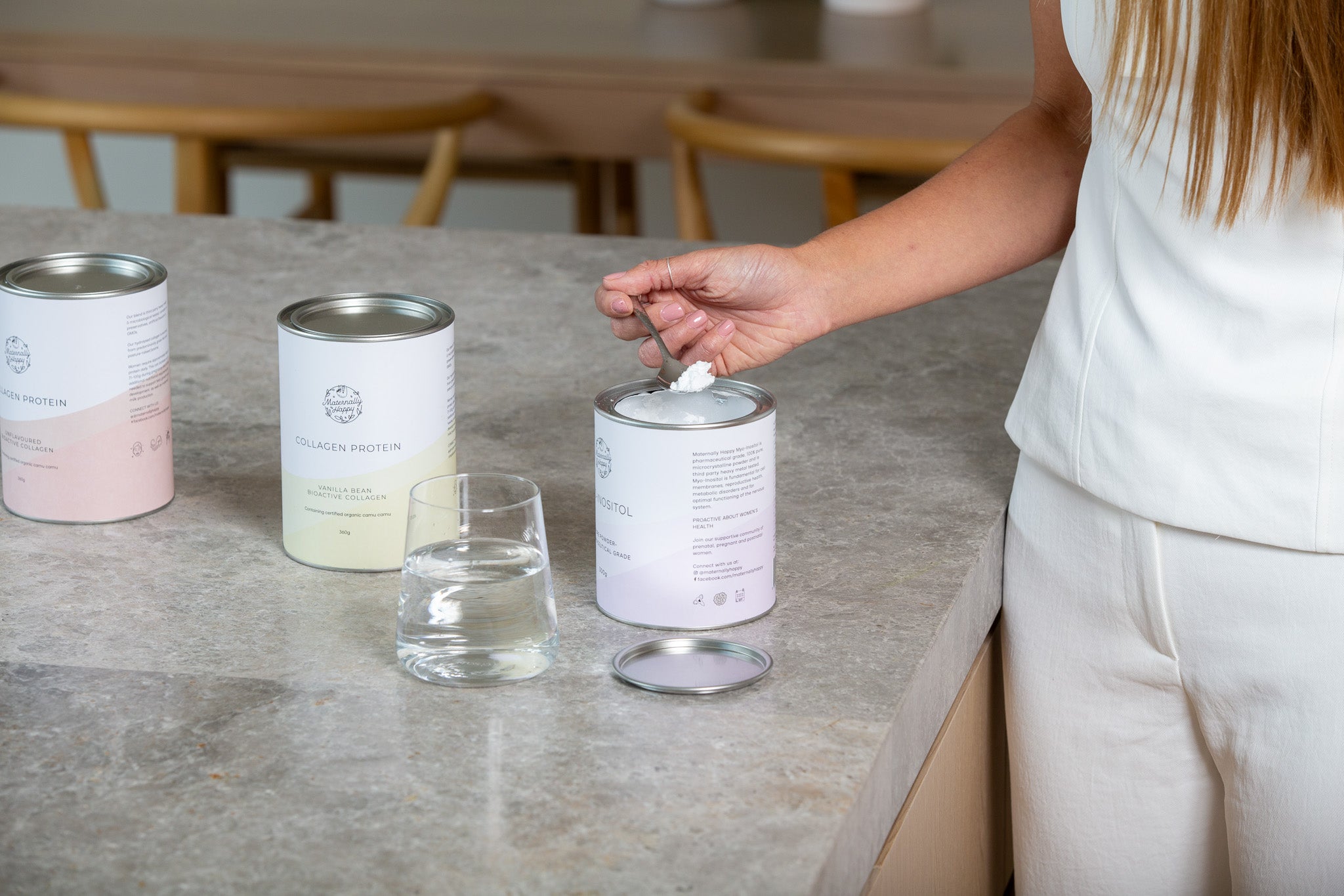 Founder Caitlin standing at a kitchen bench with Maternally Happy supplement tins, sharing her personal PCOS story