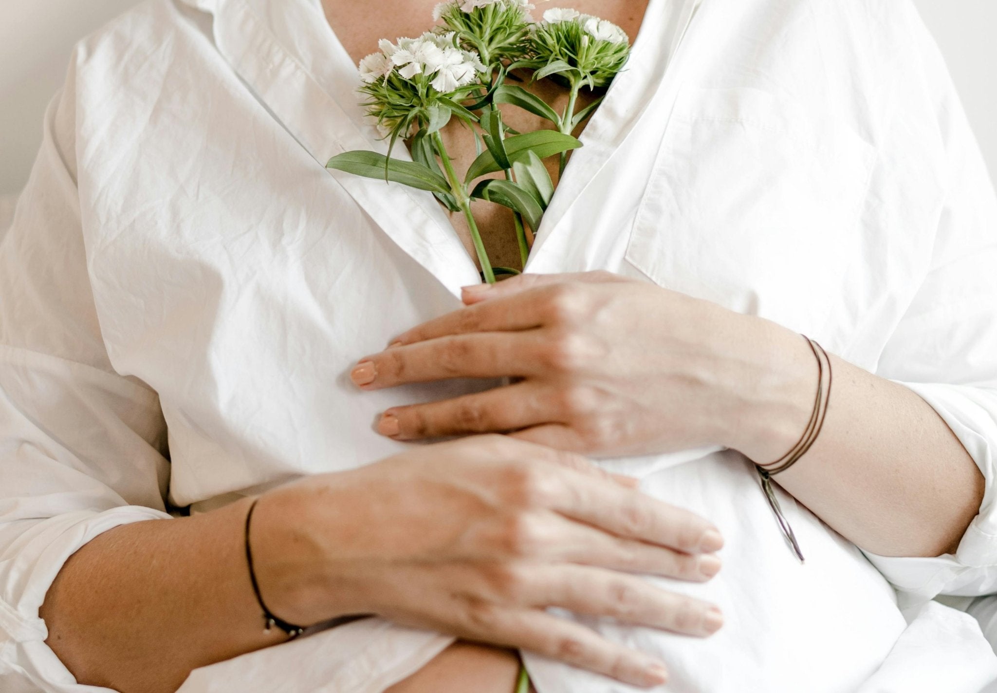 Pregnant woman holding flowers over her belly — symbolising pre-pregnancy preparation and fertility health